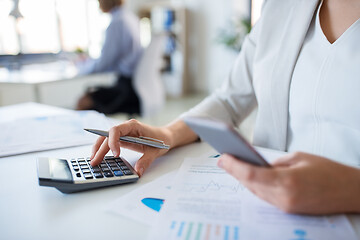 Image showing businesswoman with calculator working at office