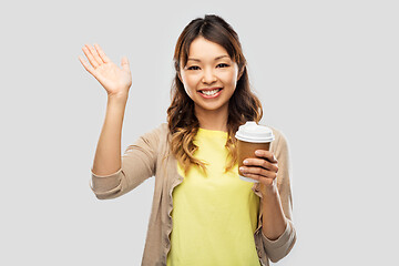 Image showing happy asian woman drinking coffee and waving hand