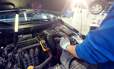 Image showing auto mechanic man with multimeter testing battery