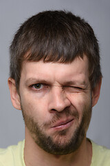 Image showing Close-up portrait of a man of European appearance who squeezed his right eye tightly