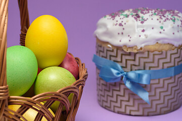 Image showing Colored Easter eggs in a basket, Easter cake on the right in the background