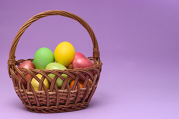 Image showing Basket with easter eggs on a dark pink background