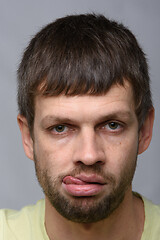 Image showing Portrait of a sad man of European appearance with his tongue hanging out, close-up