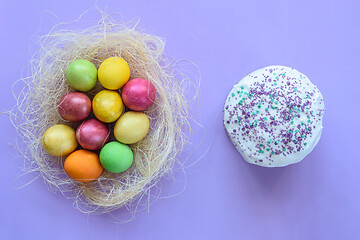 Image showing Easter eggs in a makeshift nest on a purple background, next to Easter cake