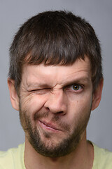 Image showing Close-up portrait of a man of European appearance who squeezed his left eye tightly