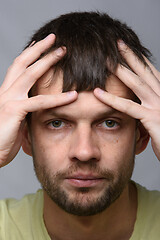 Image showing Close-up portrait of a man of European appearance clutching his head with his hands