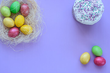 Image showing Easter eggs in a makeshift nest on a purple background, next to it is Easter cake and three eggs