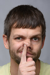 Image showing Portrait of a man of European appearance, who put his finger in his nose, close-up