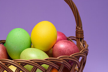 Image showing Colored easter eggs in a basket on a purple background