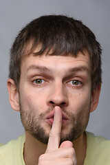 Image showing Portrait of a man of European appearance who put a finger to his mouth, gesture of silence, close-up