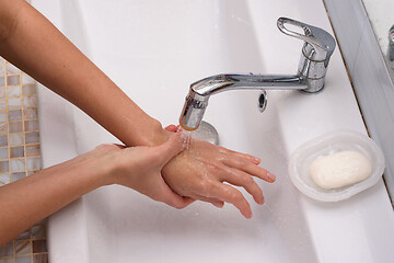 Image showing The girl brought the burn place under a stream of water for first aid