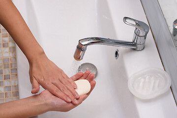 Image showing Girl soaping her hands with soap in the washbasin