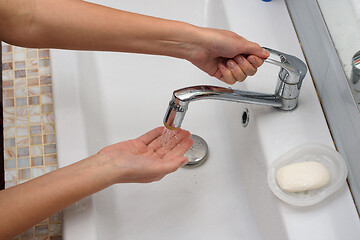 Image showing The girl opens the handle of the mixer in order to wash her hands