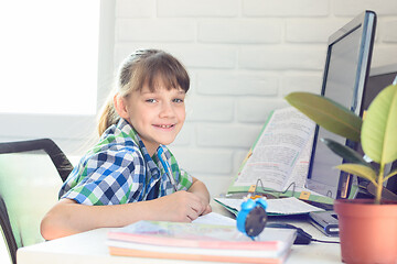 Image showing Happy schoolgirl is studying at home and looked into the frame