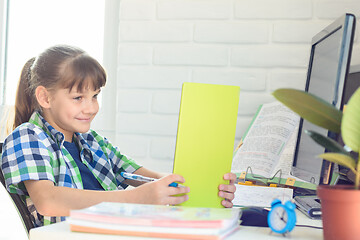 Image showing Smiling schoolgirl cheerfully watches a video tutorial on a tablet computer