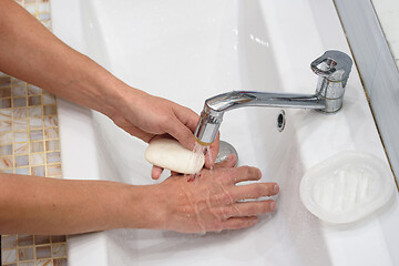 Image showing A man provides first aid for cutting his hands, washing the wound with soap