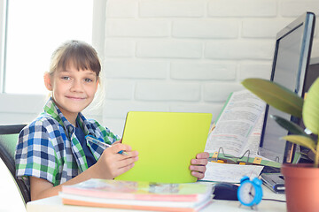 Image showing A ten-year-old girl is studying remotely at home and cheerfully looked into the frame.