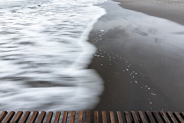 Image showing Wave rolls ashore, long exposure black and white photography