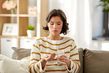 Image showing sick woman taking medicine with water at home