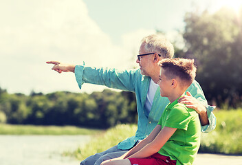 Image showing grandfather and grandson sitting on river berth