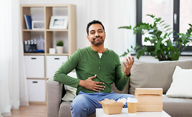 Image showing pleased indian man eating takeaway food at home