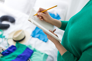 Image showing woman going on trip and making list in notebook