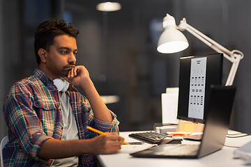 Image showing creative man with laptop working at night office