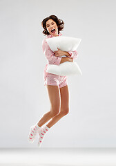 Image showing happy woman in pajama jumping with pillow