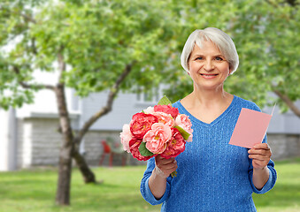 Image showing happy senior woman with flowers and greeting card