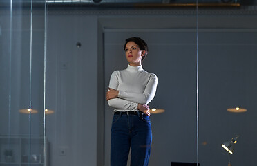 Image showing businesswoman looks at glass wall at night office