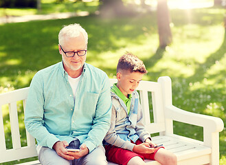 Image showing old man and boy with smartphones at summer park