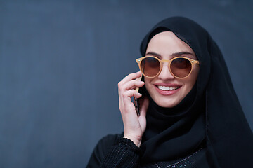 Image showing young muslim woman wearing sunglasses using smartphone