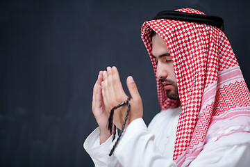 Image showing arabian man making traditional prayer to God, keeps hands in pra