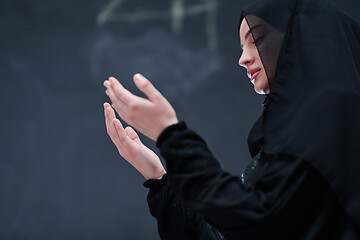 Image showing muslim woman making traditional prayer to God in front of black 