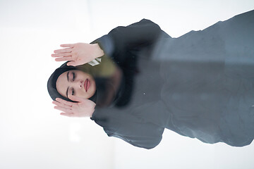 Image showing young arabian muslim woman praying on the glass floor at home