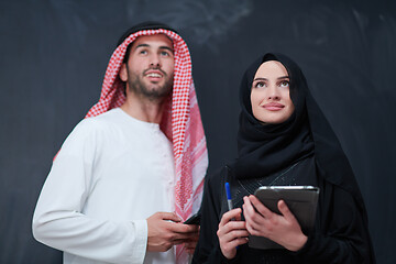 Image showing muslim couple using modern technology in front of black chalkboa