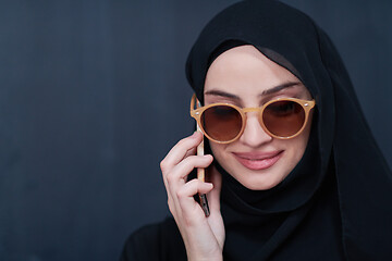 Image showing young muslim woman wearing sunglasses using smartphone