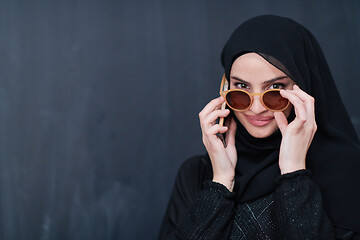 Image showing young muslim woman wearing sunglasses using smartphone