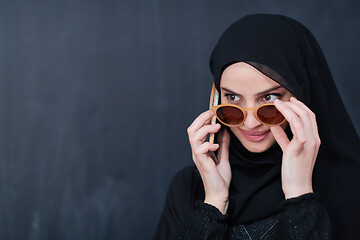 Image showing young muslim woman wearing sunglasses using smartphone