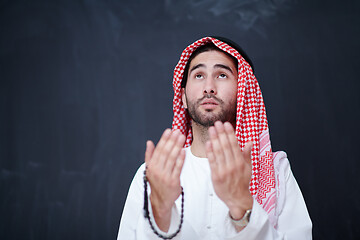 Image showing arabian man making traditional prayer to God, keeps hands in pra