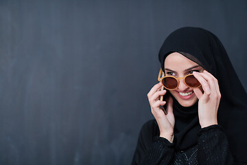 Image showing young muslim woman wearing sunglasses using smartphone