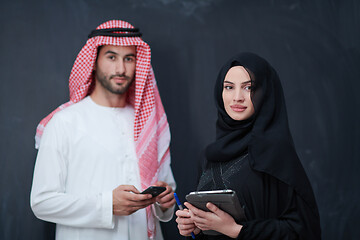 Image showing muslim couple using modern technology in front of black chalkboa