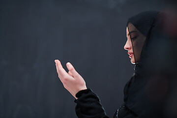 Image showing muslim woman making traditional prayer to God in front of black 