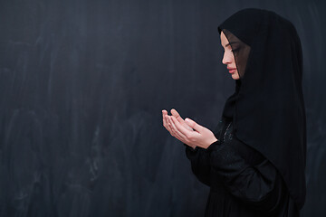 Image showing muslim woman making traditional prayer to God in front of black 