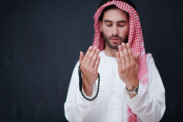 Image showing arabian man making traditional prayer to God, keeps hands in pra