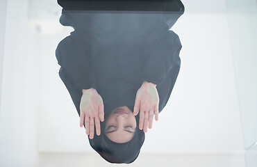 Image showing young arabian muslim woman praying on the glass floor at home