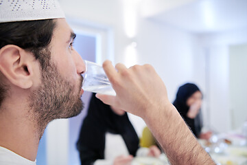 Image showing Muslim family having Iftar dinner drinking water to break feast