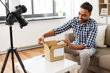 Image showing male video blogger opening parcel box at home