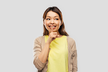 Image showing happy asian woman with finger on lips