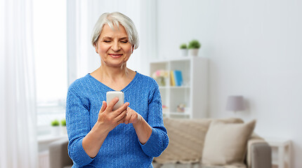 Image showing smiling senior woman using smartphone at home